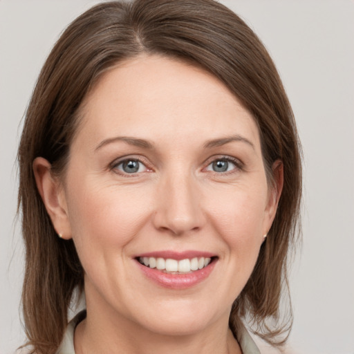 Joyful white young-adult female with medium  brown hair and grey eyes