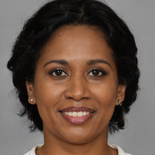 Joyful black adult female with medium  brown hair and brown eyes