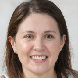 Joyful white adult female with long  brown hair and grey eyes