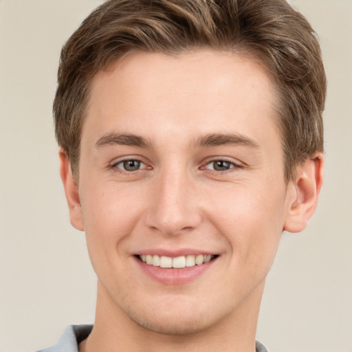 Joyful white young-adult male with short  brown hair and grey eyes