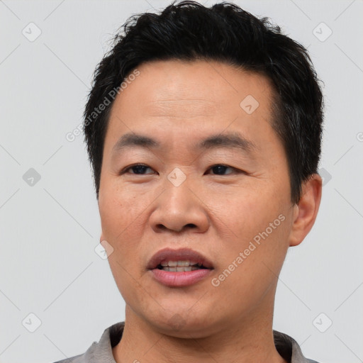 Joyful asian adult male with short  black hair and brown eyes