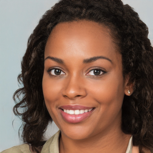 Joyful black young-adult female with long  black hair and brown eyes