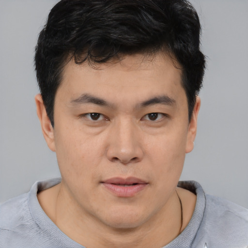 Joyful asian young-adult male with short  brown hair and brown eyes