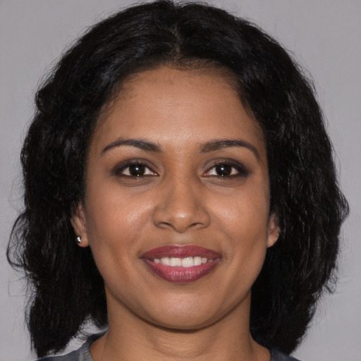 Joyful black young-adult female with long  brown hair and brown eyes