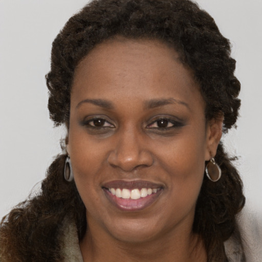 Joyful black young-adult female with long  brown hair and brown eyes