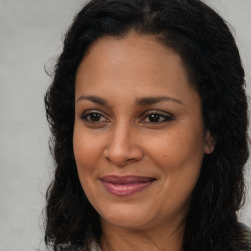 Joyful latino adult female with long  brown hair and brown eyes