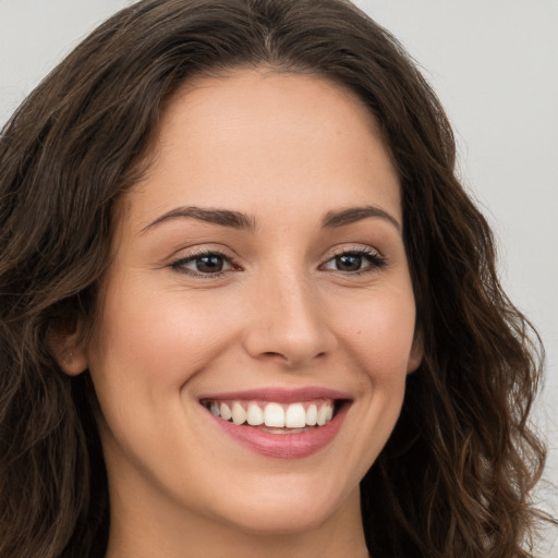 Joyful white young-adult female with long  brown hair and brown eyes