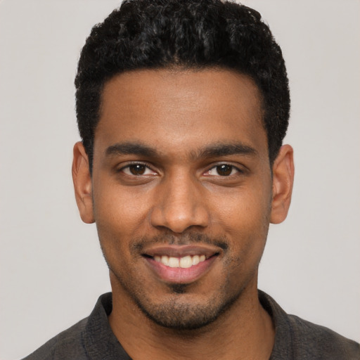 Joyful black young-adult male with short  black hair and brown eyes