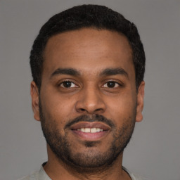 Joyful latino young-adult male with short  black hair and brown eyes