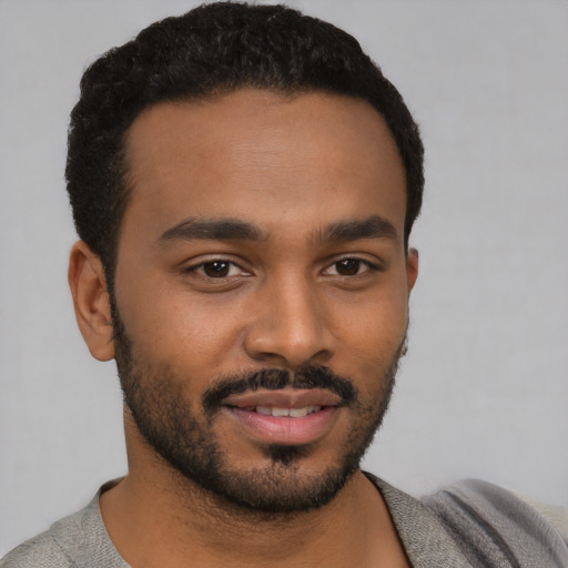 Joyful black young-adult male with short  black hair and brown eyes