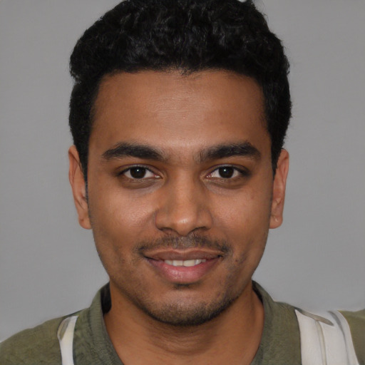 Joyful black young-adult male with short  black hair and brown eyes