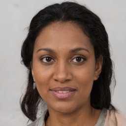 Joyful black young-adult female with long  brown hair and brown eyes