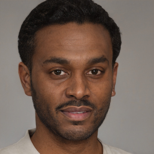 Joyful black young-adult male with short  brown hair and brown eyes