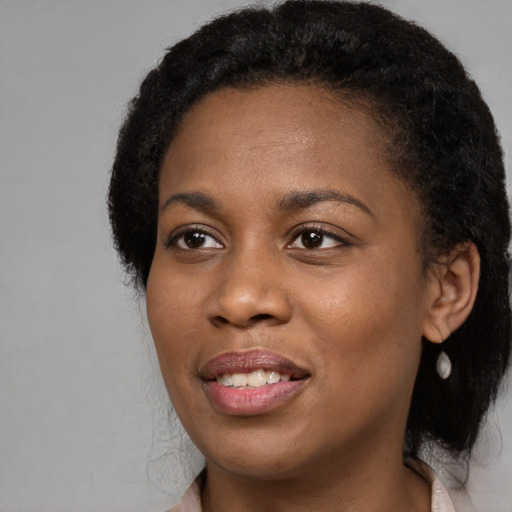 Joyful black young-adult female with long  black hair and brown eyes