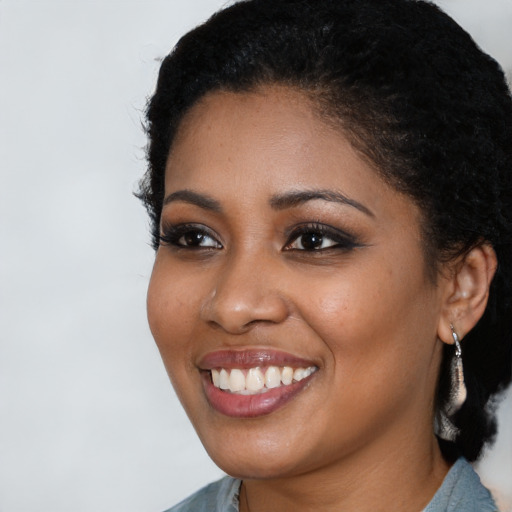 Joyful black young-adult female with long  black hair and brown eyes