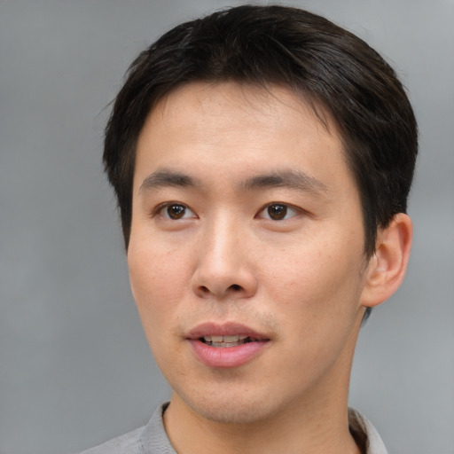 Joyful asian young-adult male with short  brown hair and brown eyes