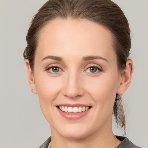 Joyful white young-adult female with medium  brown hair and grey eyes