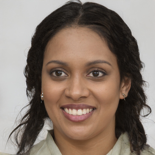 Joyful black young-adult female with long  brown hair and brown eyes