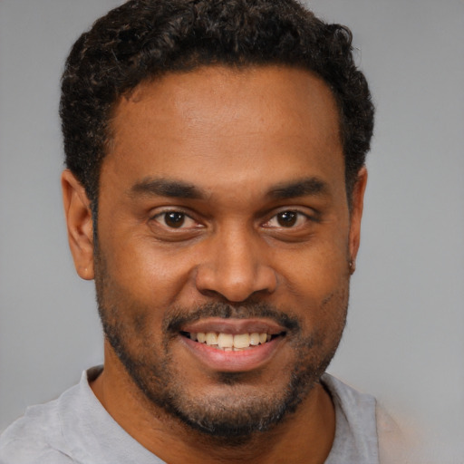 Joyful black young-adult male with short  brown hair and brown eyes