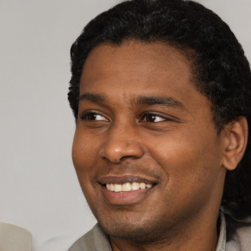 Joyful black young-adult male with short  black hair and brown eyes