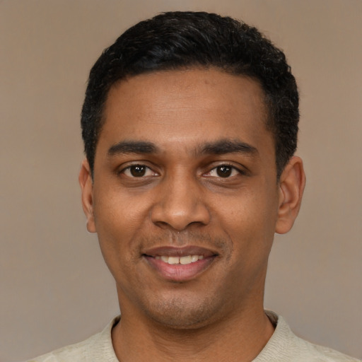 Joyful black young-adult male with short  black hair and brown eyes