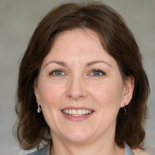 Joyful white adult female with medium  brown hair and blue eyes