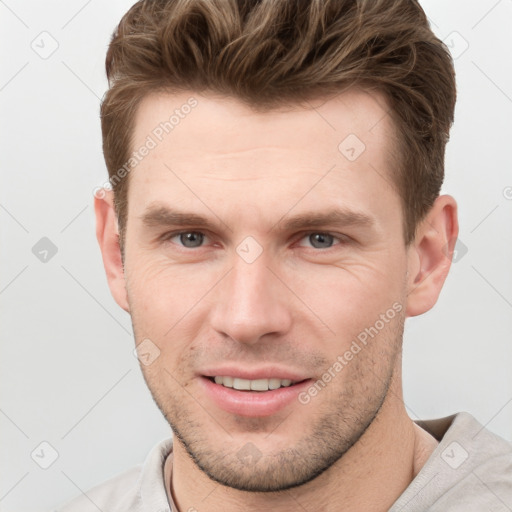 Joyful white young-adult male with short  brown hair and grey eyes