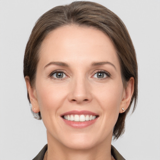 Joyful white young-adult female with medium  brown hair and grey eyes