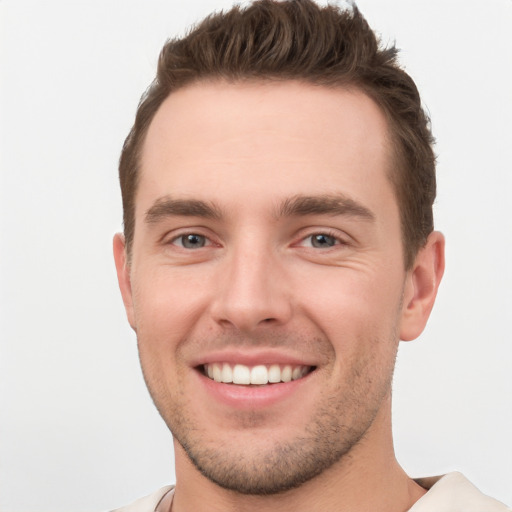 Joyful white young-adult male with short  brown hair and grey eyes