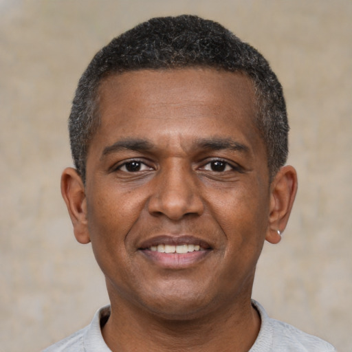 Joyful black young-adult male with short  black hair and brown eyes