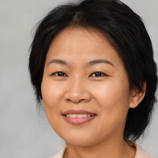 Joyful asian adult female with medium  brown hair and brown eyes