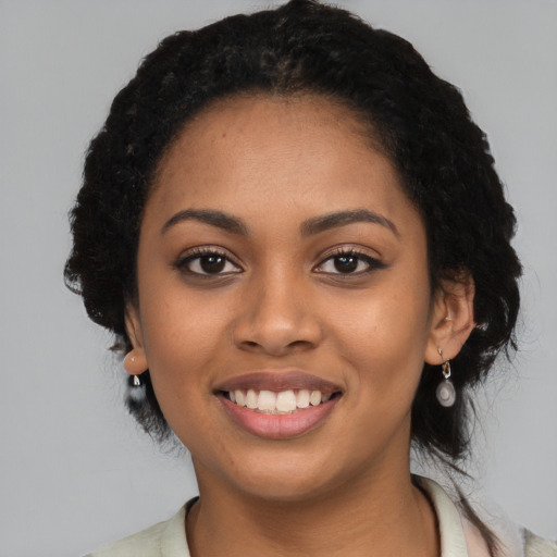 Joyful black young-adult female with long  black hair and brown eyes