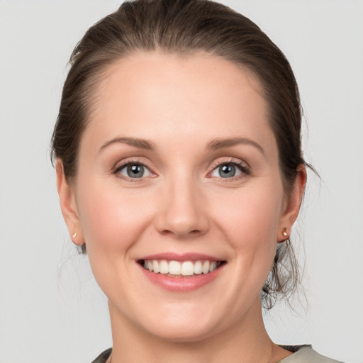 Joyful white young-adult female with medium  brown hair and grey eyes