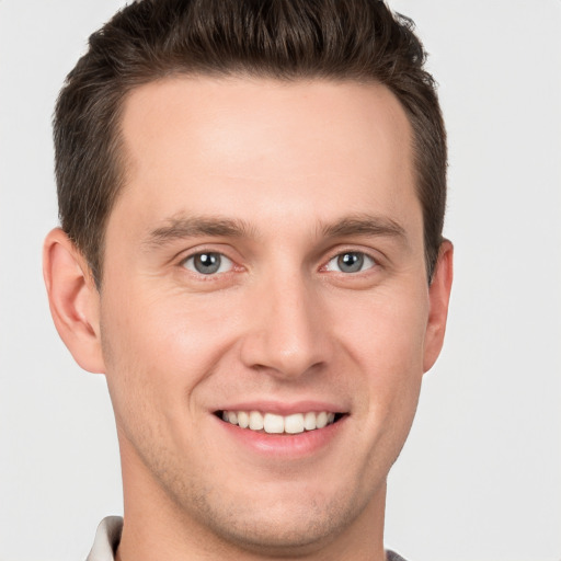 Joyful white young-adult male with short  brown hair and grey eyes