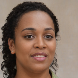 Joyful black young-adult female with long  brown hair and brown eyes