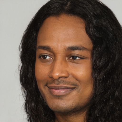 Joyful black young-adult male with long  black hair and brown eyes