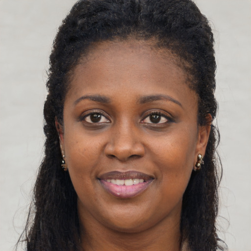 Joyful black young-adult female with long  brown hair and brown eyes