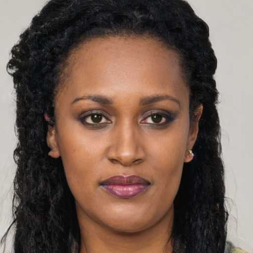 Joyful black young-adult female with long  black hair and brown eyes