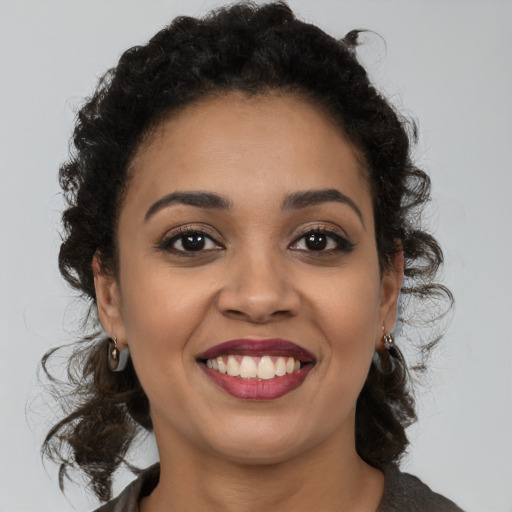 Joyful black young-adult female with long  brown hair and brown eyes