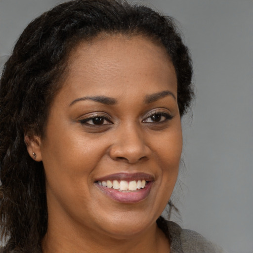 Joyful black young-adult female with long  brown hair and brown eyes