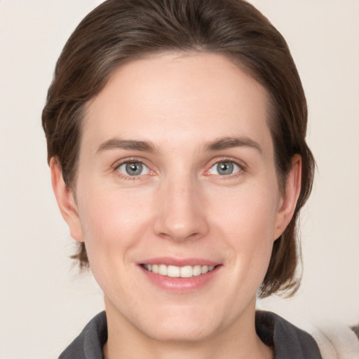 Joyful white young-adult female with medium  brown hair and grey eyes