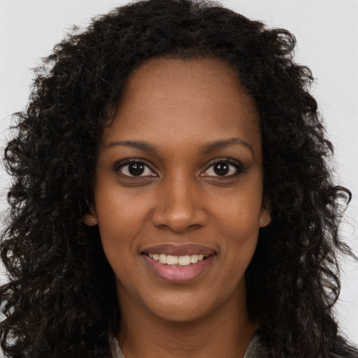 Joyful black young-adult female with long  brown hair and brown eyes