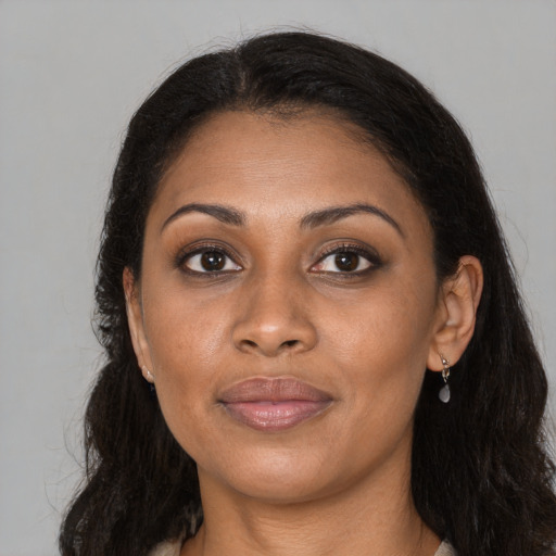 Joyful black young-adult female with long  brown hair and brown eyes
