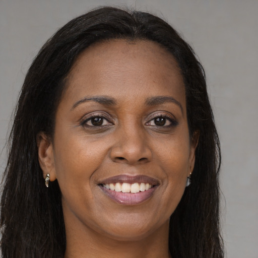 Joyful black young-adult female with long  brown hair and brown eyes