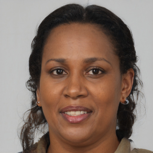 Joyful black adult female with long  brown hair and brown eyes