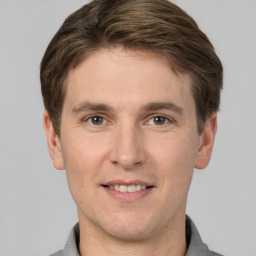 Joyful white young-adult male with short  brown hair and grey eyes