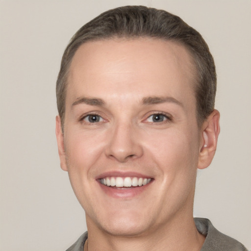 Joyful white young-adult male with short  brown hair and grey eyes