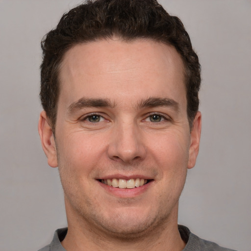 Joyful white young-adult male with short  brown hair and grey eyes