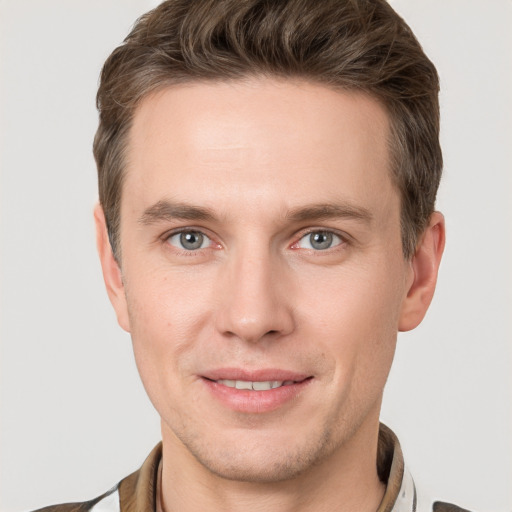 Joyful white young-adult male with short  brown hair and grey eyes