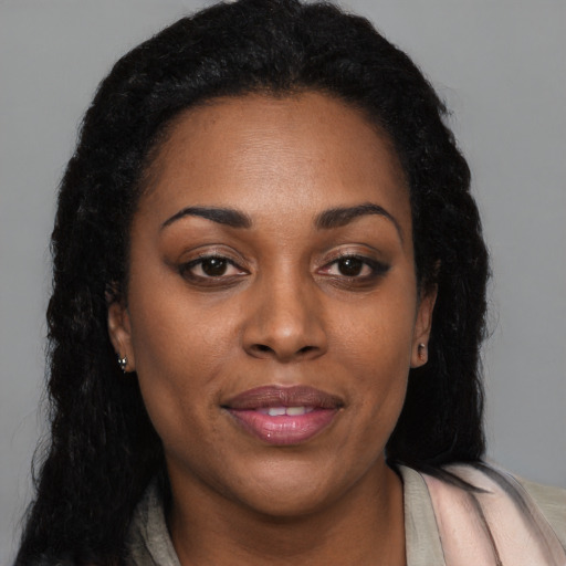 Joyful black young-adult female with long  brown hair and brown eyes